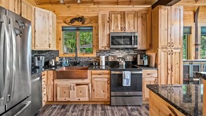 A modern kitchen with wooden cabinets, stainless steel appliances, and a large island. - 180 Views Sleeps 7 Private Hot Tub Full Kitchen (Gatlinburg)
