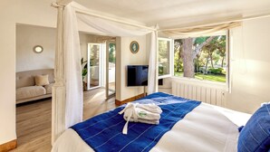 A bedroom with a canopy bed, a TV, and a view of the outdoors. - Spectacular Villa in Quinta do Lago - Private Pool, BBQ & 5-Star Concierge (Faro)