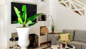 A modern living room with a fireplace, a staircase, and a large potted plant. - Spectacular Villa in Quinta do Lago - Private Pool, BBQ & 5-Star Concierge (Faro)
