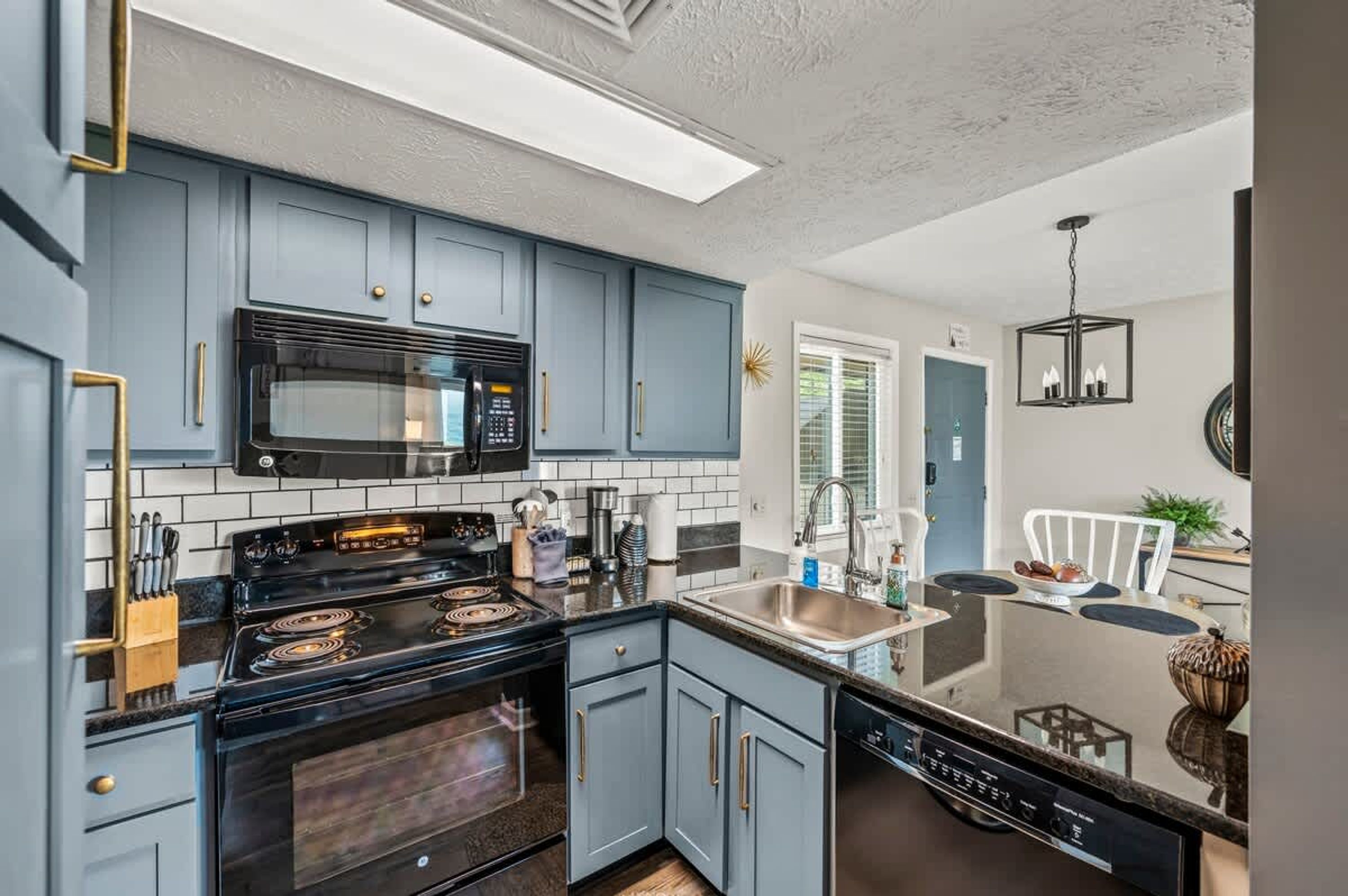 A modern kitchen with blue cabinets, a black stove, and a microwave.