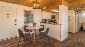 A modern kitchen with a central island, white cabinetry, and a dining area with four chairs. - Indoor Pool Access Full Kitchen Mountain Views (Gatlinburg)