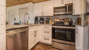 A modern kitchen with stainless steel appliances, white cabinetry, and a wooden ceiling. - Indoor Pool Access Full Kitchen Mountain Views (Gatlinburg)