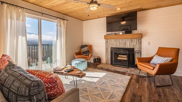 A living room with a fireplace, a ceiling fan, and a view of the outdoors. - Indoor Pool Access Full Kitchen Mountain Views (Gatlinburg)
