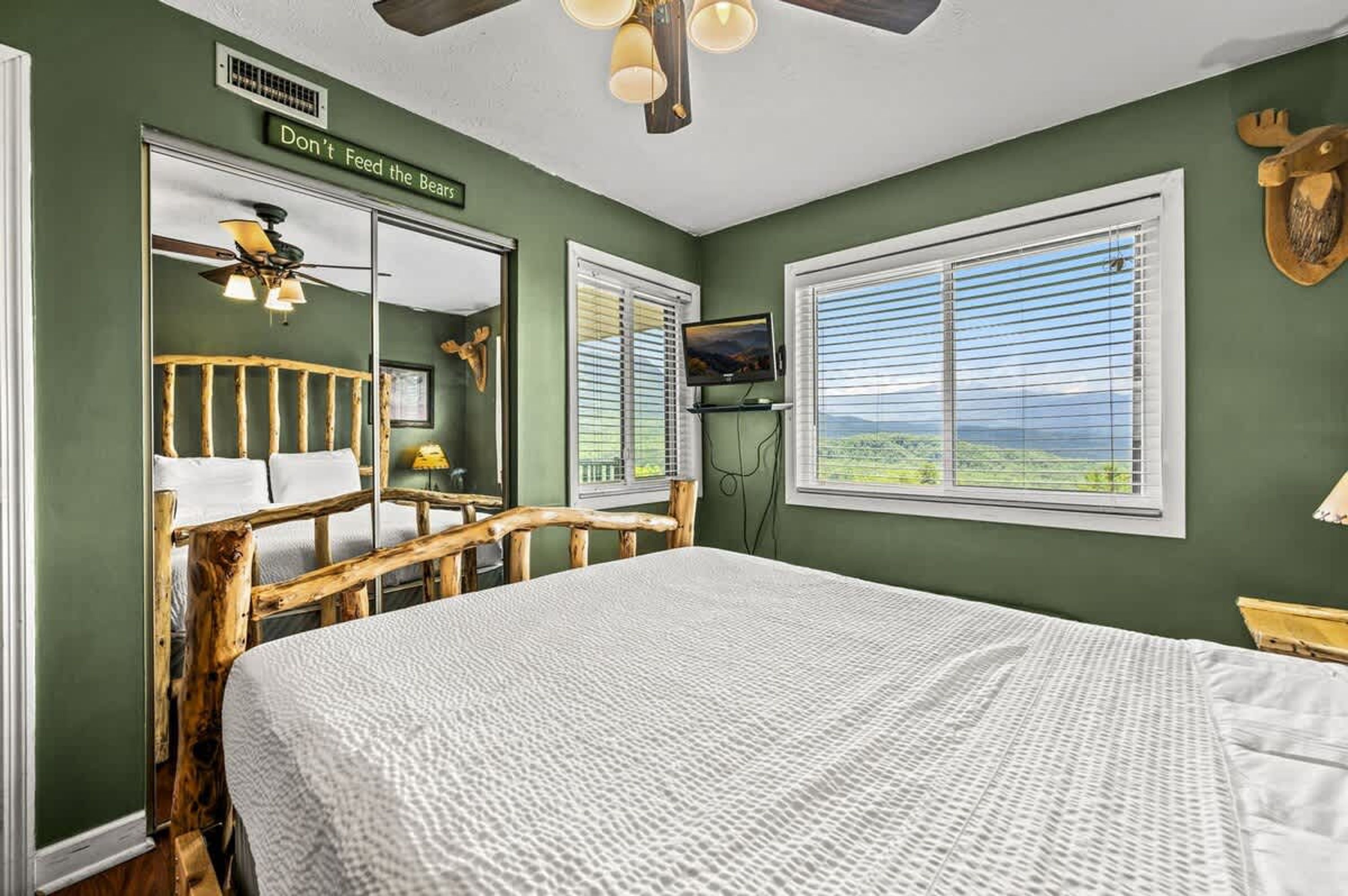 Ein Zimmer mit einem großen Bett, einem Deckenventilator, einem Fernseher und einem Fenster mit Blick.