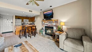 A living room with a fireplace, a television mounted above it, and a ceiling fan. - Sleeps 6 Indoor Pool Hot Tub Mountain Views (Gatlinburg)