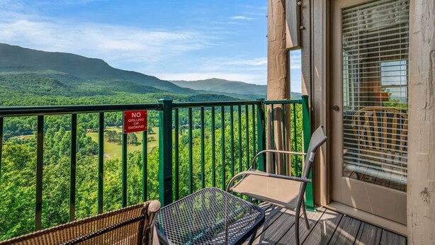 A balcony with a view of green hills, a 'No Grilling/Smoking' sign, and a chair. - Sleeps 6 Indoor Pool Hot Tub Mountain Views (Gatlinburg)