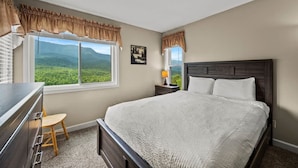 A bedroom with a large bed, a desk, a chair, a nightstand with a lamp, and a window with curtains. - Sleeps 6 Indoor Pool Hot Tub Mountain Views (Gatlinburg)