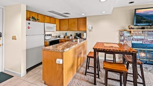 A modern kitchen with wooden cabinets, a granite countertop, and a stone fireplace. - Sleeps 6 Indoor Pool Hot Tub Mountain Views (Gatlinburg)