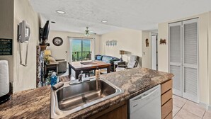 A kitchen with a granite countertop, stainless steel sink, and a dishwasher. There is a dining area with a table and chairs, and a view of the outdoors through a window. - Sleeps 6 Indoor Pool Hot Tub Mountain Views (Gatlinburg)