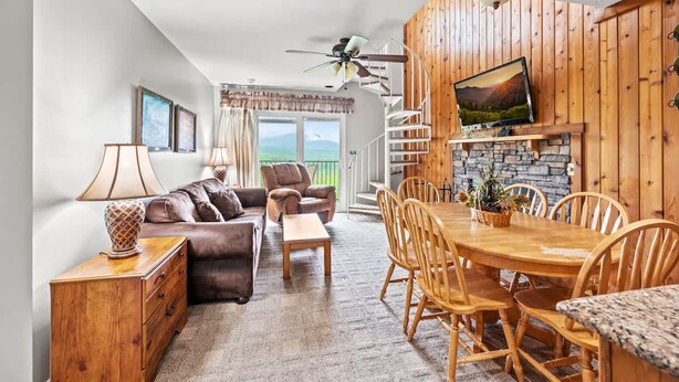A spacious living room with a fireplace, wooden dining table, and comfortable seating. - Sleeps 8 Pool Playground Mountain Views Hot Tub (Gatlinburg)