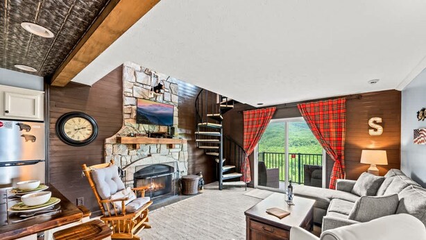 A modern living room with a stone fireplace, a dining area with a wooden table, and a cozy seating area with a sofa and chairs. - Sleeps 6 Pool Playground Mountain Views Hot Tub (Gatlinburg)
