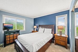 Cozy retreat with a large bed, nightstands, dresser, and TV.