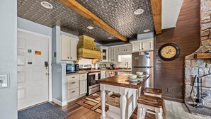 A modern kitchen with white cabinetry, a central island, and a stone fireplace. - Sleeps 6 Pool Playground Mountain Views Hot Tub (Gatlinburg)