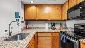 A kitchen with granite countertops, wooden cabinets, stainless steel appliances, and a microwave. - Indoor Pool Hot Tub Sauna Sleeps 6 Full Kitchen (Gatlinburg)