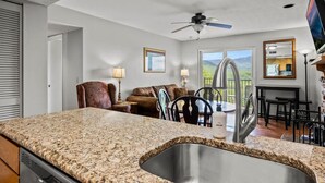 A modern kitchen with granite countertops, a stainless steel sink, and a ceiling fan. - Indoor Pool Hot Tub Sauna Sleeps 6 Full Kitchen (Gatlinburg)