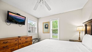 A bedroom with a bed, dresser, TV, and windows. - Indoor Pool Hot Tub Sauna Sleeps 6 Full Kitchen (Gatlinburg)