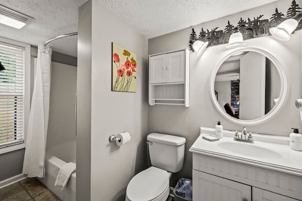 A bathroom with a toilet, sink, and shower.