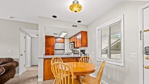 A compact kitchen with wooden cabinets, a built-in microwave, and a dining area with a round table and chairs. - Indoor Pool Mountain Views Hot Tub Sauna (Gatlinburg)