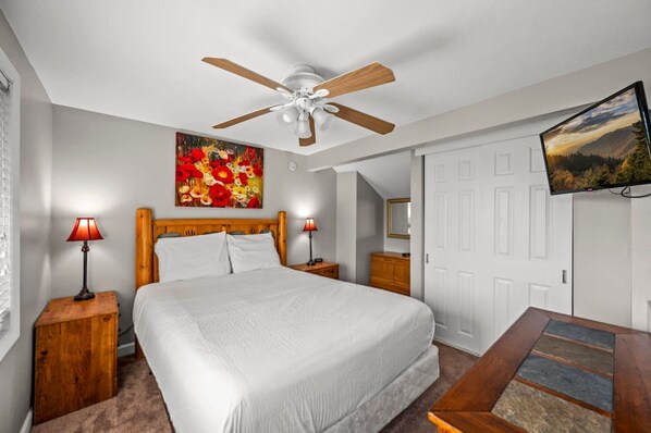 A bedroom with a bed, a ceiling fan, a painting, a TV, and a door. - Indoor Pool Mountain Views Hot Tub Sauna (Gatlinburg)