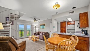 A spacious living area with a dining table, a sofa, and a staircase leading to a balcony. - Indoor Pool Mountain Views Hot Tub Sauna (Gatlinburg)