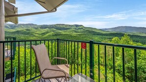 A balcony with a chair, a table, and a 'NO GRILLING' sign. - Sleeps 6 Mountain Views Heated Pool Playground (Gatlinburg)