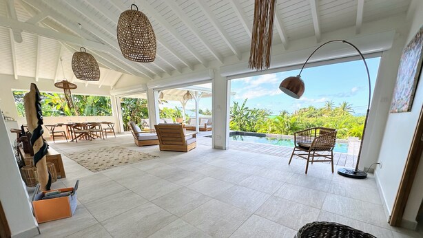 A spacious indoor area with a pool view, wicker furniture, and a tiled floor. - Grey houses villa a beautiful property with a pool and spacious areas (Grand-Bourg)