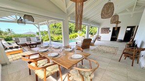 A spacious dining area with a wooden table set for six, surrounded by wooden chairs with fur throw cushions. - Grey houses villa a beautiful property with a pool and spacious areas (Grand-Bourg)