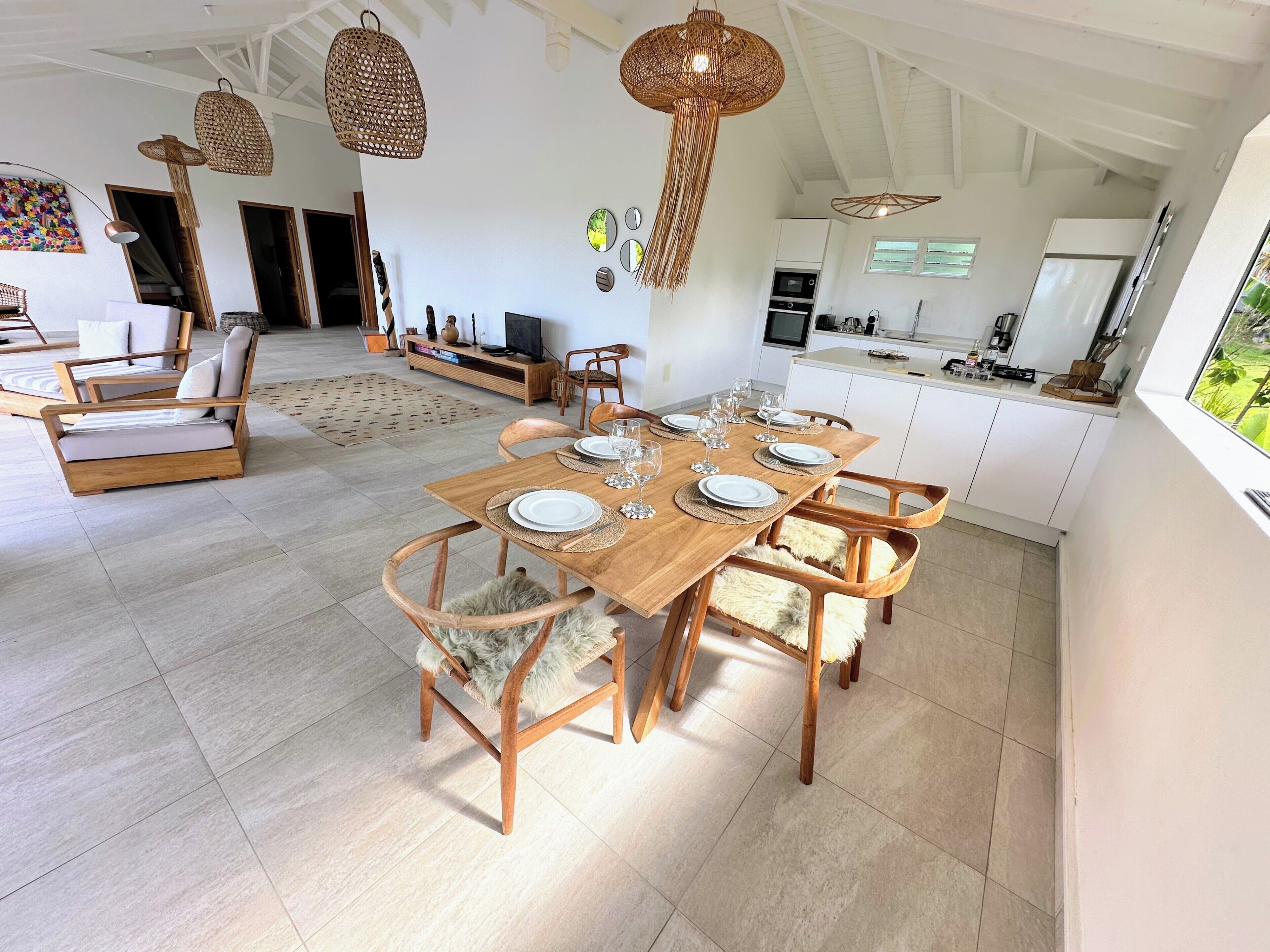 Un comedor espacioso con una mesa de madera preparada para seis personas, rodeada de sillas de madera con suaves cojines de piel.