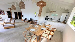A spacious dining area with a wooden table set for six, surrounded by wooden chairs with fur throw cushions. - Grey houses villa a beautiful property with a pool and spacious areas (Grand-Bourg)