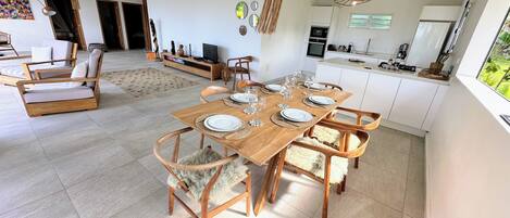 Un comedor espacioso con una mesa de madera preparada para seis personas, rodeada de sillas de madera con suaves cojines de piel.