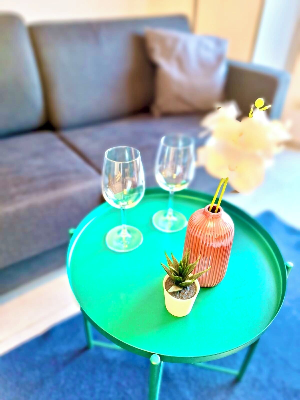 Ein grüner Tisch mit drei Weingläsern und einem kleinen Topfpflanzen.