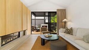 Een moderne woonkamer met een open haard, een bank, een salontafel en uitzicht op de omgeving.
