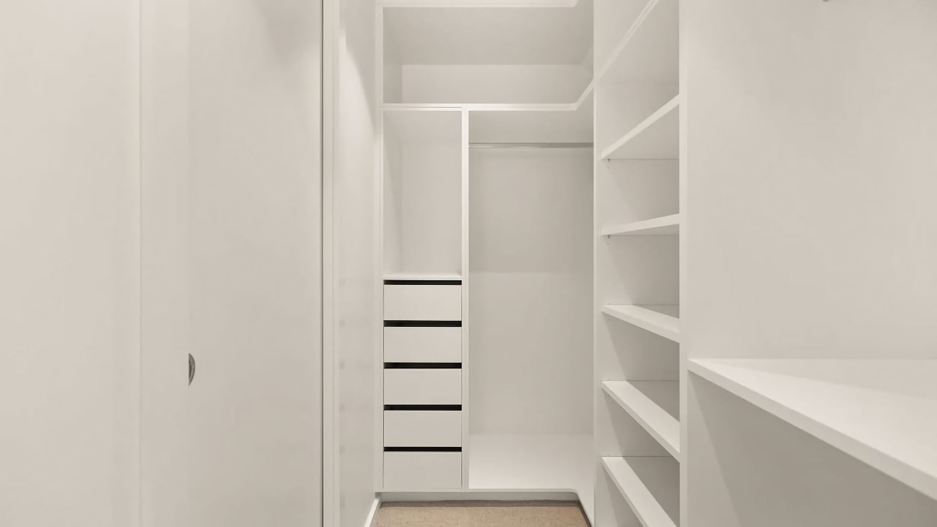 En smal, avlång klädkammare med flera hyllor och lådor, med en minimalistisk design.
