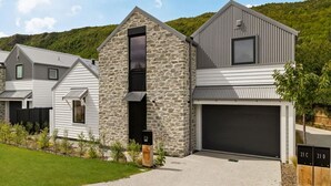 Een modern huis met twee verdiepingen, een stenen gevel, een garage en een verzorgd gazon.