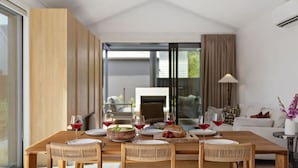 Een moderne eetruimte met een houten tafel gedekt voor vier personen, omringd door rieten stoelen.
