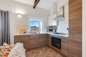 Una cocina moderna con armarios de madera, microondas, estufa y ventana con vistas a edificios.