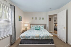 Une chambre à coucher avec un lit, une table de chevet, une lampe et une porte.