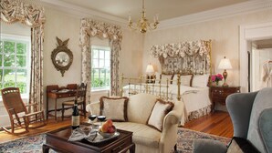 Une chambre à coucher classique, avec un lit à baldaquin, un lustre et une vue sur le jardin par la fenêtre.