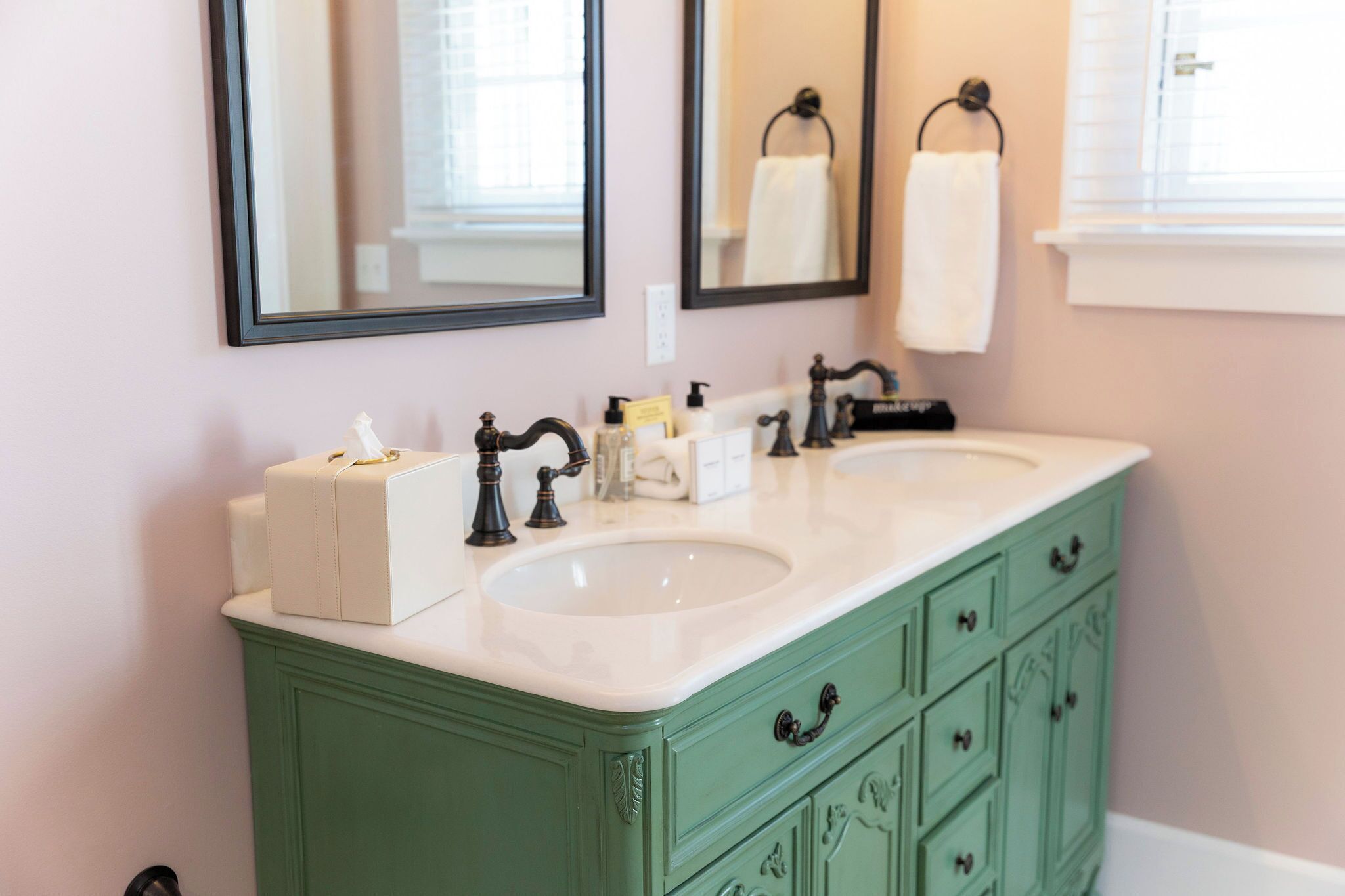 A bathroom with two sinks, a mirror, and a green vanity.