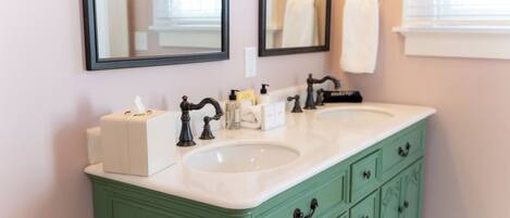A bathroom with two sinks, a mirror, and a green vanity.