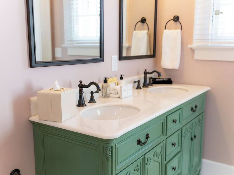 A bathroom with two sinks, a mirror, and a green vanity.