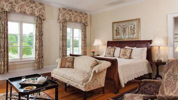 Une chambre traditionnelle avec un lit, deux chaises, une table avec un service à thé et un tableau au mur.