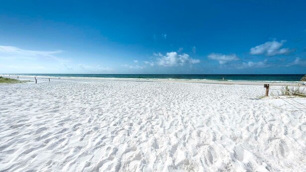 Un'ampia spiaggia sabbiosa con cielo azzurro limpido e mare calmo.