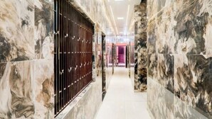 A hallway with marble walls and a modern design, leading to a room with a pink interior. - Shree Kashi Vishwanath Home Stay (Varanasi)