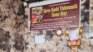 A reception desk with a marble wall backdrop, a signboard for Shree Kashi Vishwanath Home Stay, and a clock. - Shree Kashi Vishwanath Home Stay (Varanasi)