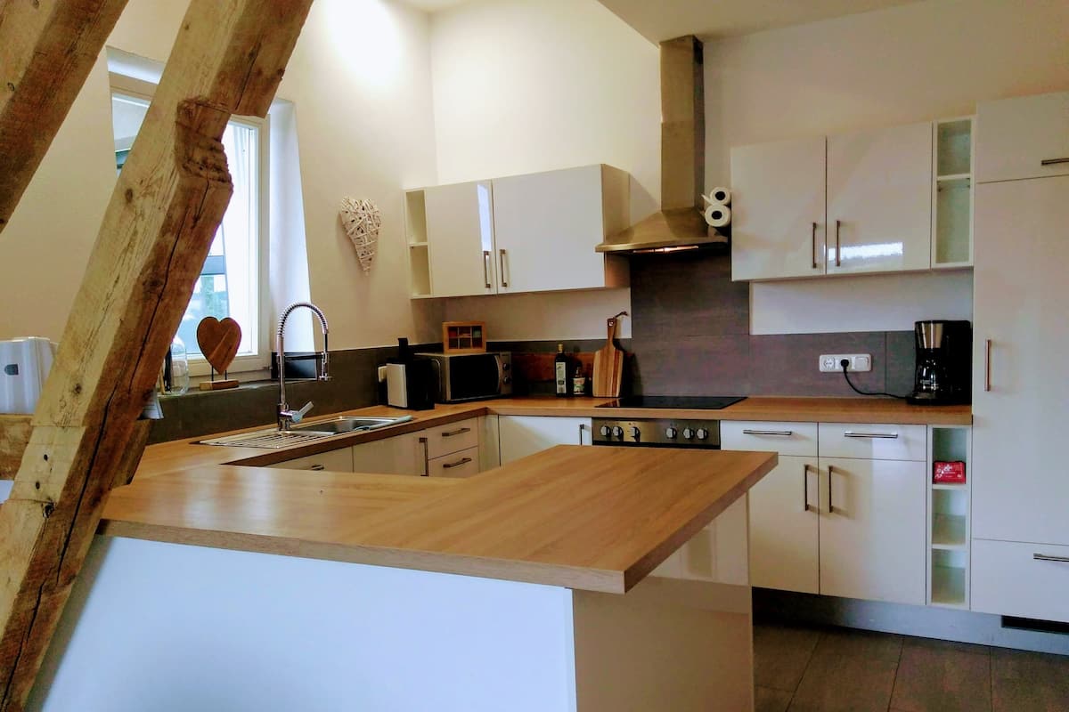 Eine moderne Küche mit weißen Schränken, einer Holz Arbeitsplatte, einem eingebauten Herd und einer Kaffeemaschine.
