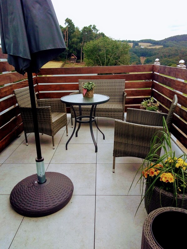 Un patio con muebles de mimbre, una mesa redonda y plantas en macetas.