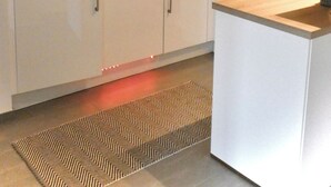 Egy modern konyha fehér szekrényekkel, mikrohullámú sütővel, kávéfőzővel és beépített sütővel.