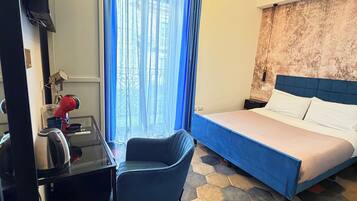 A hotel room with a bed, a desk, a chair, a coffee maker, and a window with curtains.
