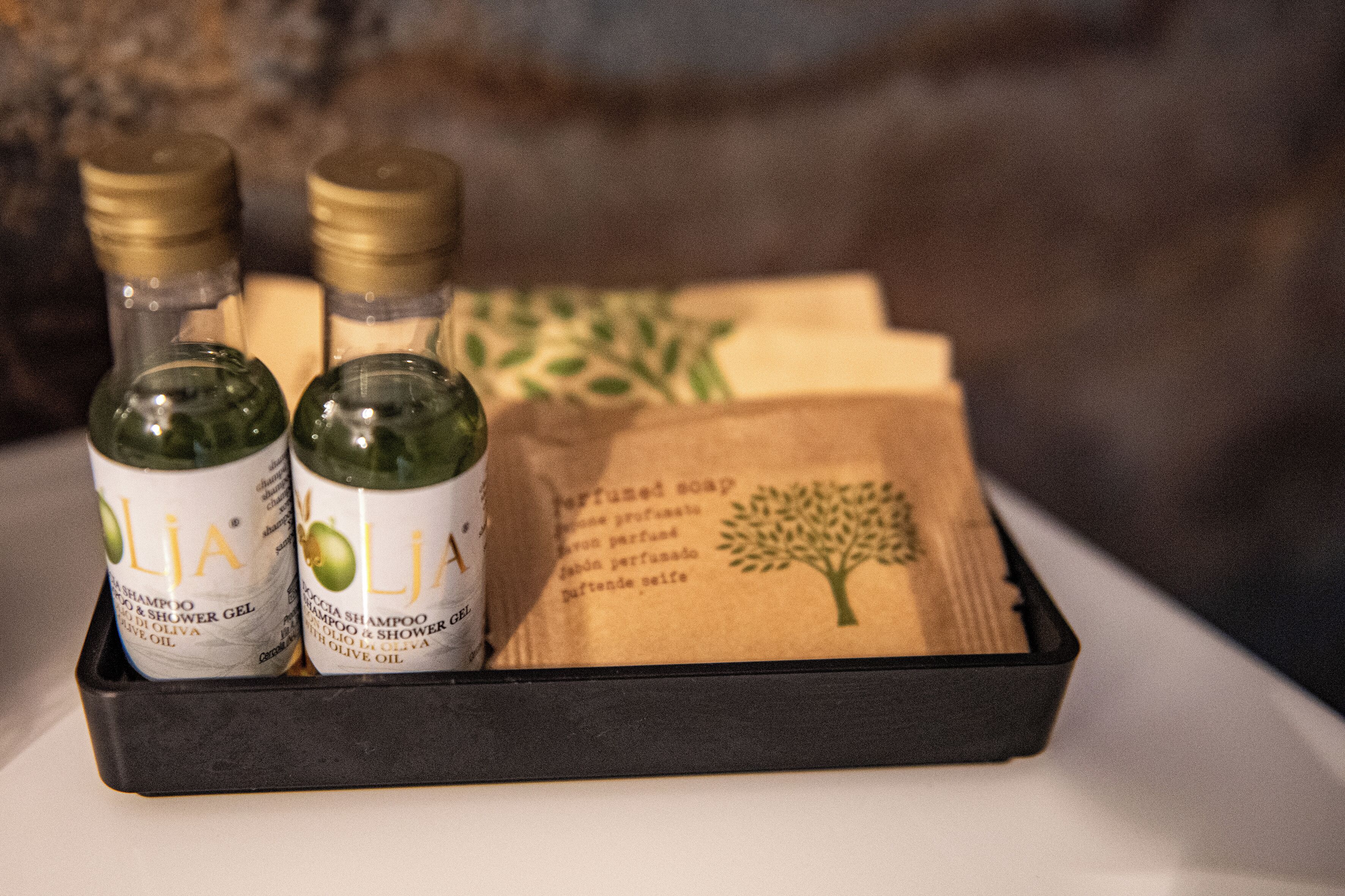 A tray containing two bottles of olive oil and a brown paper bag with a tree design.